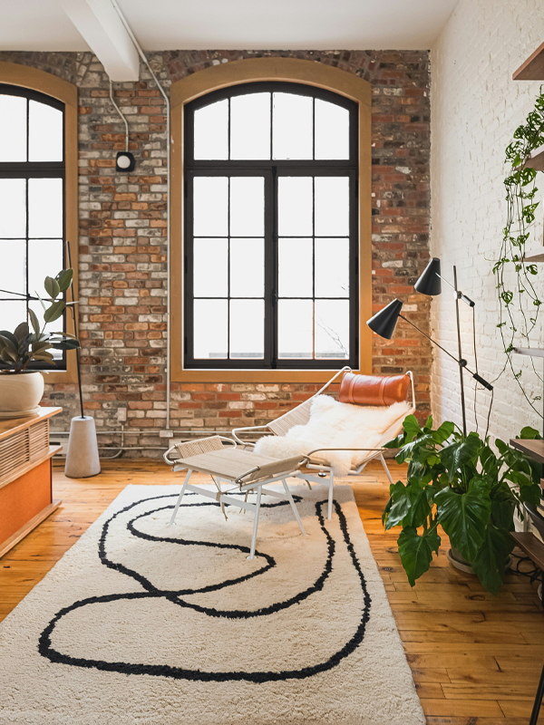 Wohnzimmer in einem oft-Apartment mit großen Fenstern, Backsteinmauer und Holzfußboden