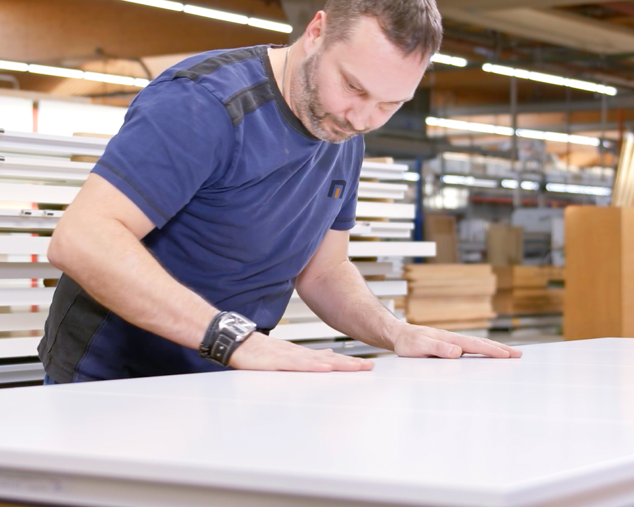 Ein Mann streicht prüfend über eine weiße Türoberfläche.