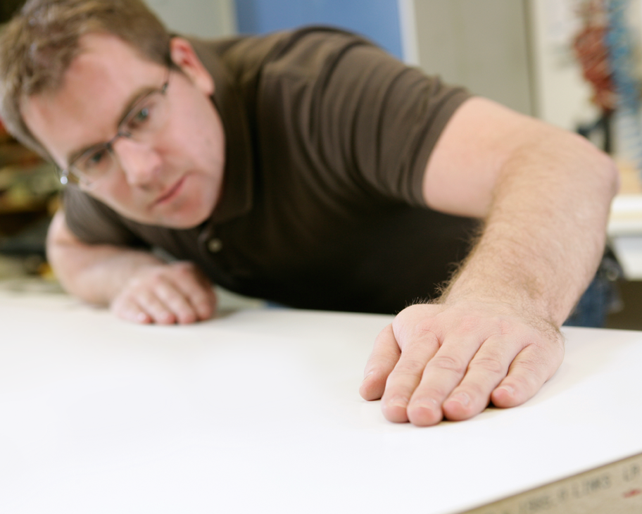 Ein Mann streicht prüfend über eine weiße Türoberfläche.