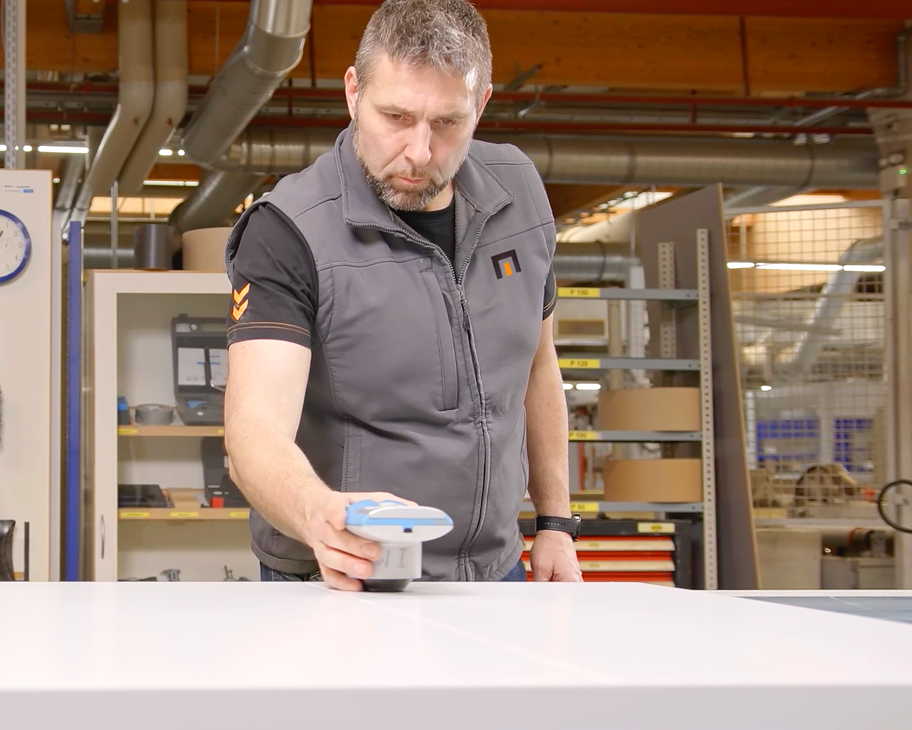 Ein Mann prüft mit einem Messgerät den Farbton einer Türoberfläche.