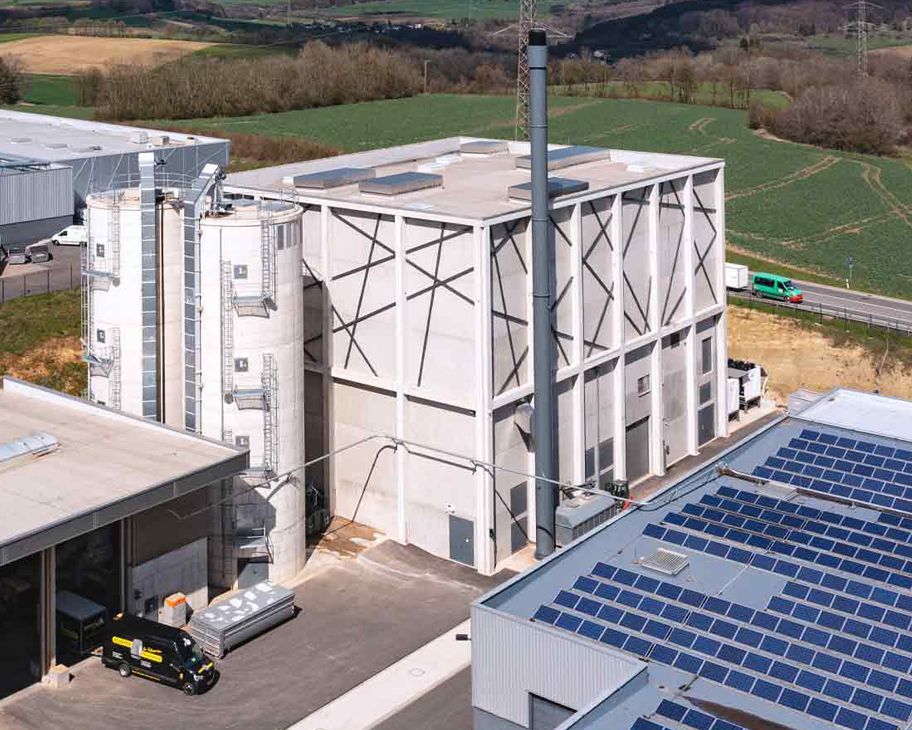 Ein Holzheizkraftwerks und eine Photovoltaikanlage auf einem Industriehallendach