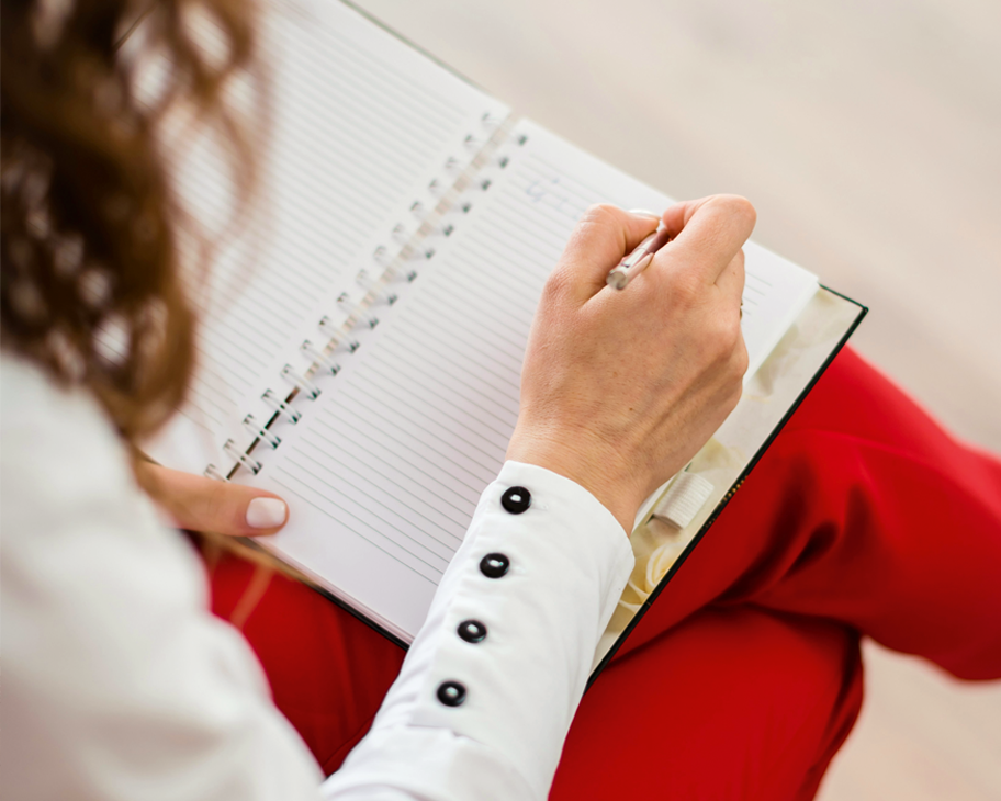 Eine Frau schreibt in ein Notizbuch.