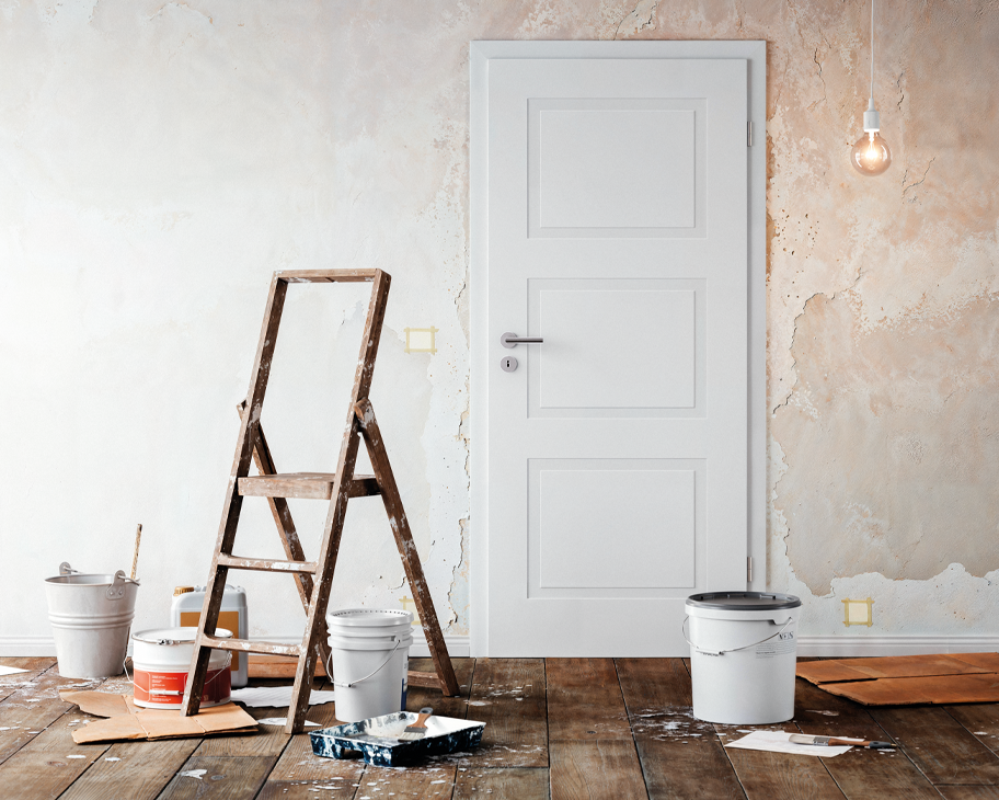 Weiße Cala-03-Stiltür in einem Raum, der renoviert wird: Farbeimer, Pappen und eine Holzleiter stehen neben dr Tür, von der Decke hängt eine nackte Glühbirne.