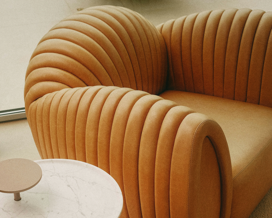 ein voluminöser, curryfarbener Ledersessel mit rundem Beistelltisch aus Marmor