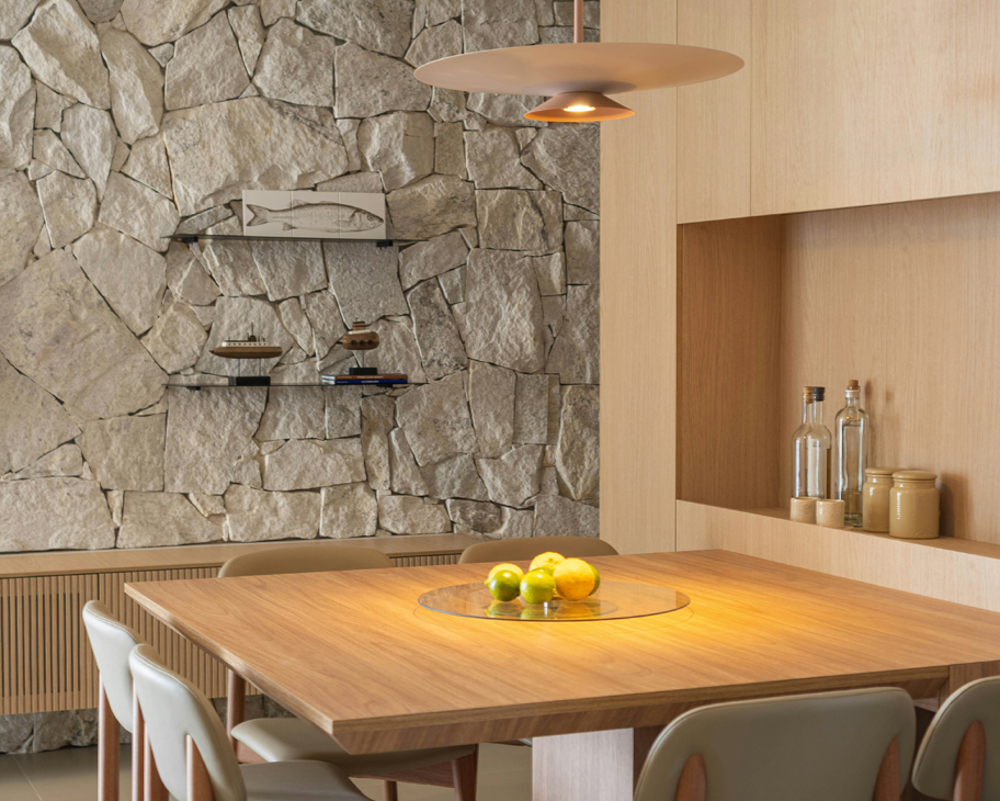 ein Esszimmer mit Naturstein-Wand und Möbeln aus Holz