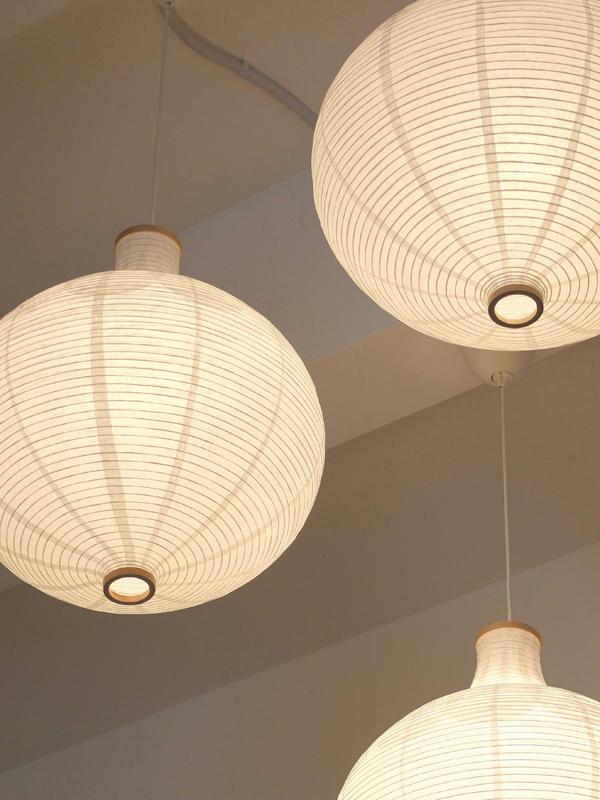 Drei weiße Papierleuchten hängen an einer weißen Decke.