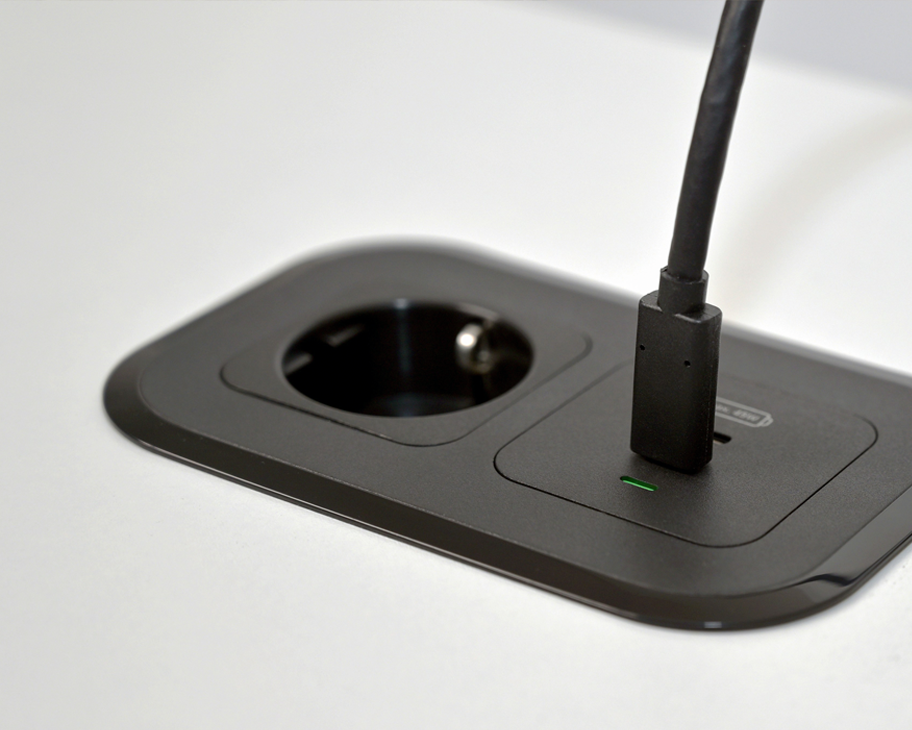 Nahaufnahme von einem in eine Tischoberfläche integrierten Netzanschlusses