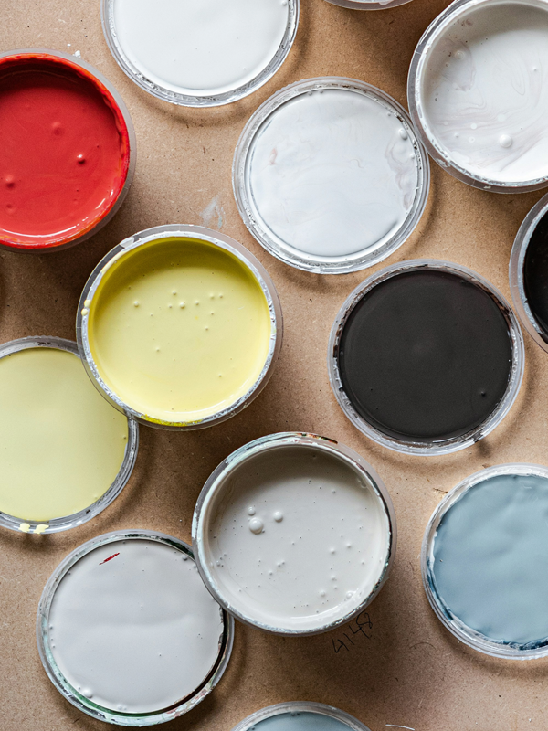 geöffnete Farbeimer mit roter, gelber, weißer, grauer, schwarzer und blauer Farbe